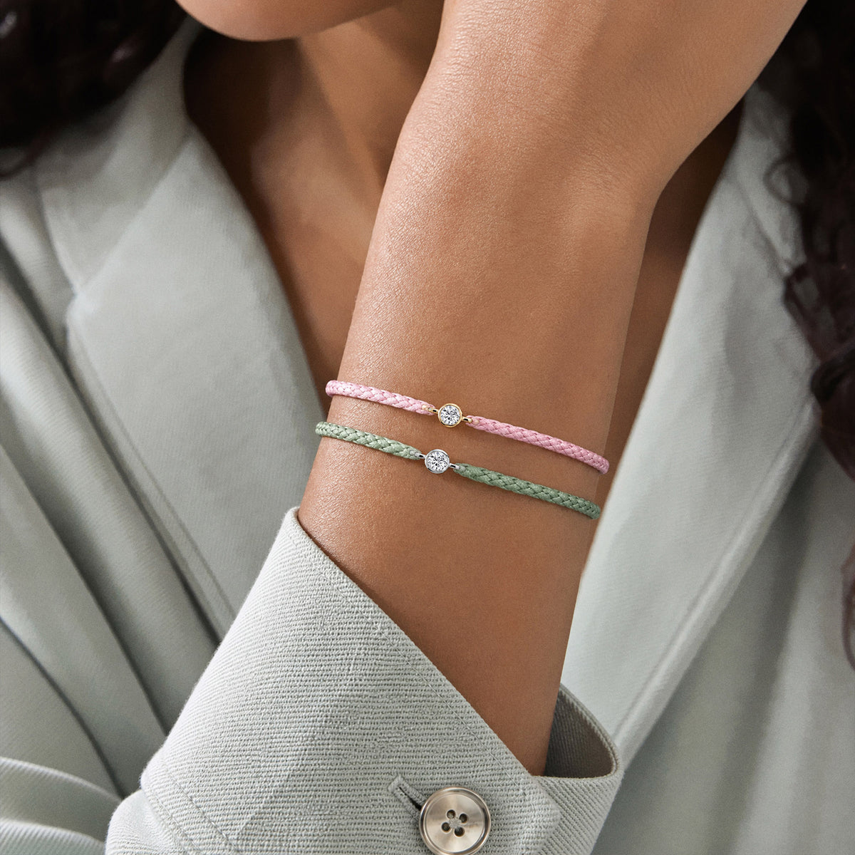 Rosa und hellgrüne Textilarmbänder mit 0.20 ct Lab Grown Diamonds am Handgelenk einer Frau